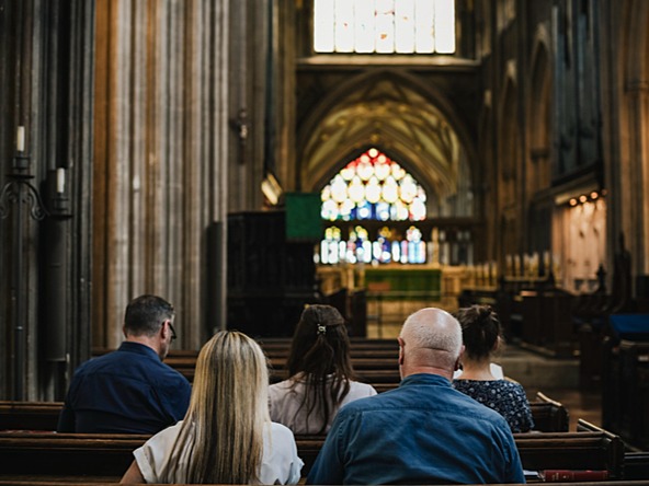 members of congregation shown from behind, sitting on pews in church